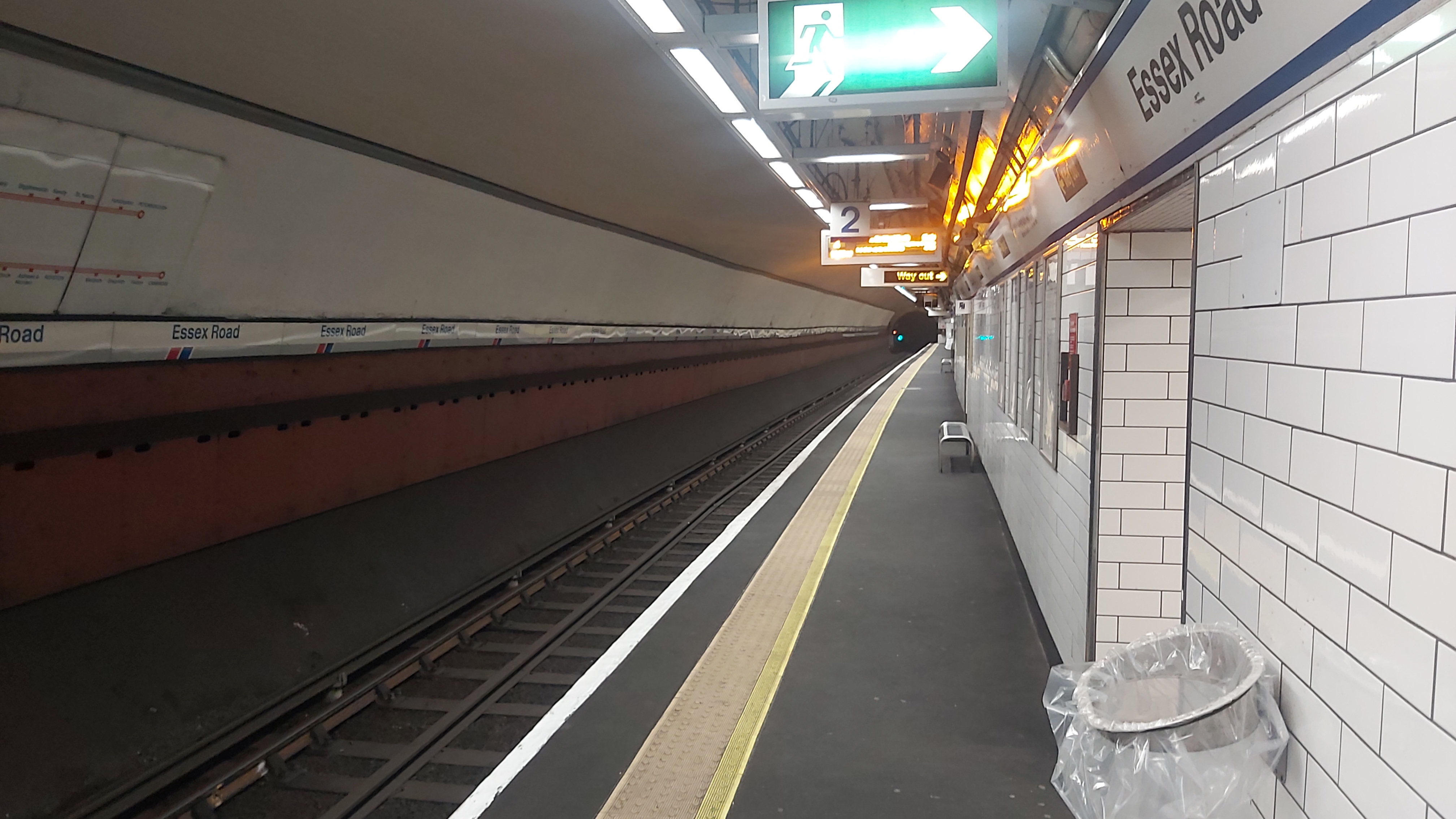 The northbound platform at Essex Road station. Part of a Network SouthEast route map is on the left wall. The platform is completely deserted.